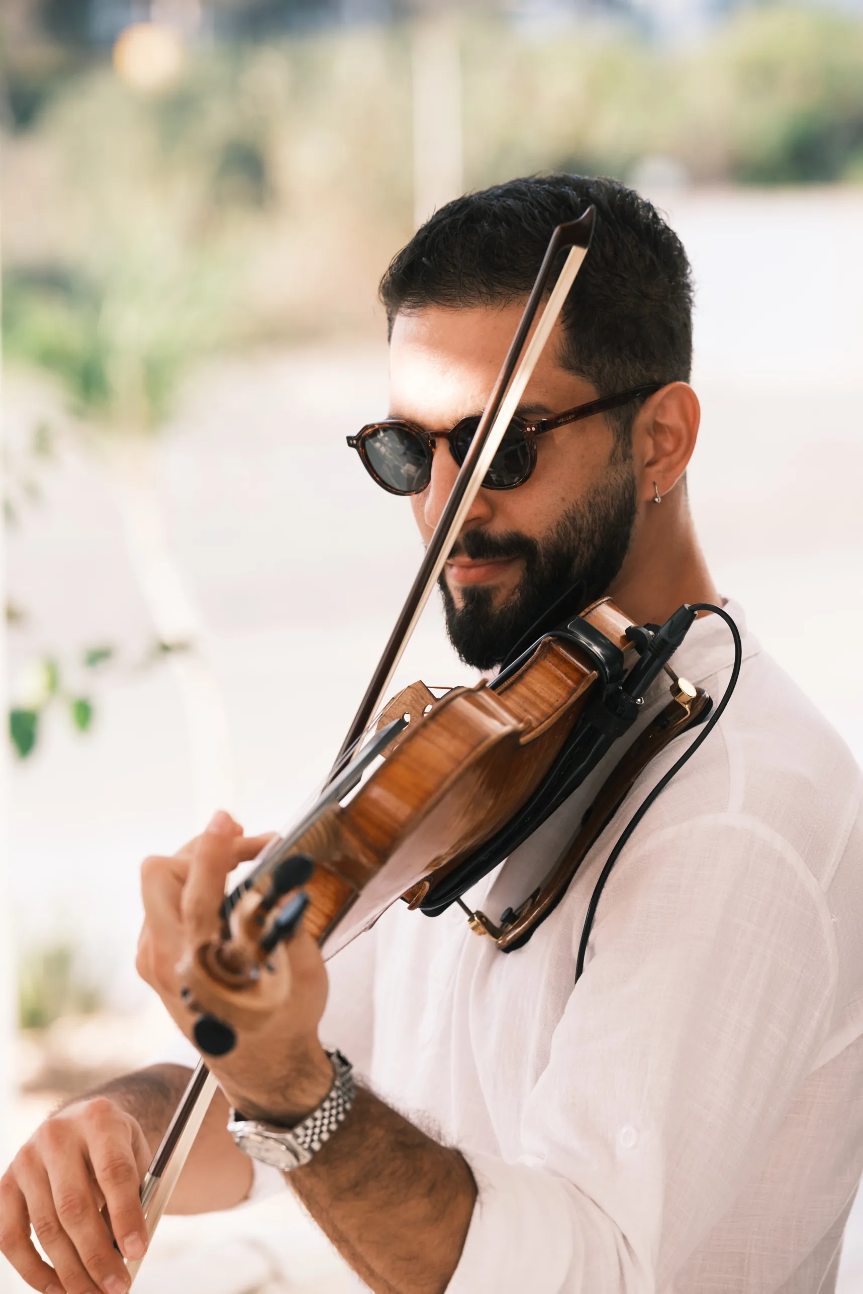 Marios Pavlou playing violin in sunglasses, bow crossing his face